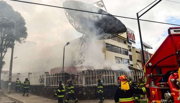 Firefighters work to extinguish a fire at Ecuadorean TV station Teleamazonas offices in Quito