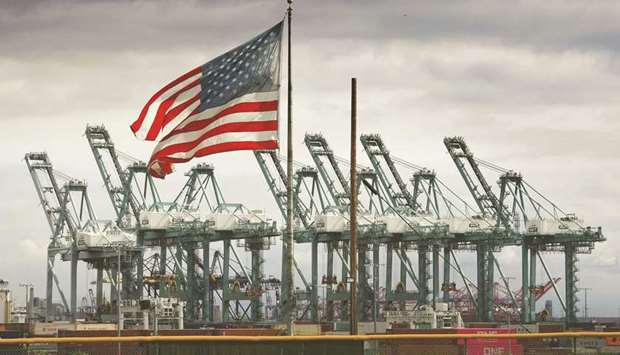 In this file photo taken on March 4, 2019, a US flag flies over shipping cranes and containers in Long Beach, California. US President Donald Trumpu2019s 18-month trade clash with Chinese leader Xi Jinping has already put global growth under pressure.