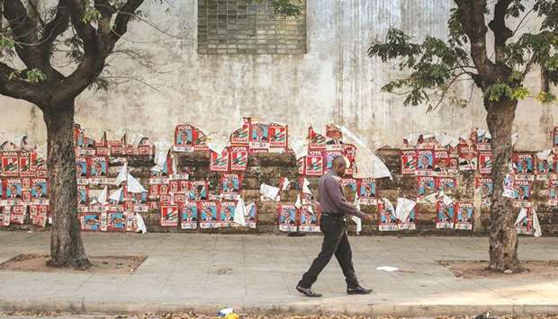 A man walks by a wall plastered with Mozambican ruling party Mozambique Liberation Front (Frelimo) presidential candidate Felipe Nyusi posters in Central Maputo, yesterday.
