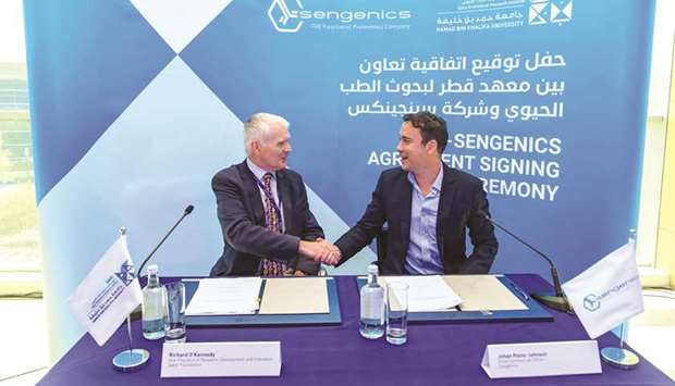 Representatives from Qatar Biomedical Research Institute (QBRI) and Sengenics shake hands after signing the agreement.