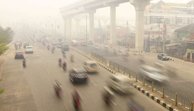 Motorists pass through a road as smoke covers the city due to the forest fires in Palembang, South Sumatra province of Indonesia yesterday.
