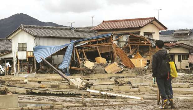 A man looks at flood-damaged homes in Nagano yesterday.