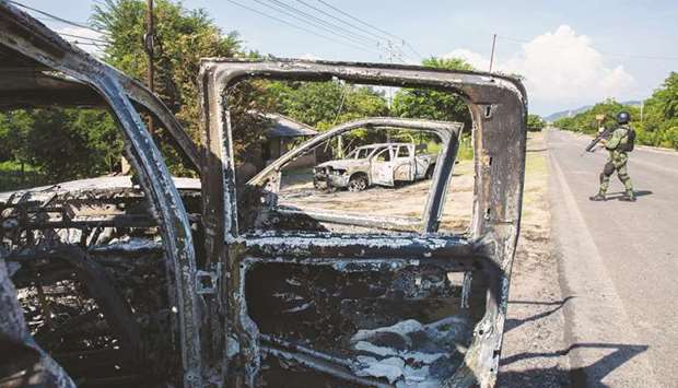 A soldier inspects police vehicles torched by gunmen who also killed 14 police officers in an ambush in the community of Aguililla, in the Mexican state of Michoacan.