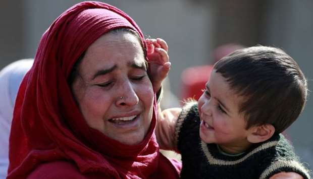 A Kashmir woman mourns as she carries a child during the funeral procession of Nasir Ahmad, a suspected separatist militant, after he was killed in a gun battle with Indian soldiers