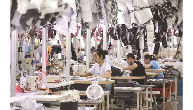 Employees producing down coats at a factory for Chinese clothing company Bosideng in Nantong in Chinau2019s eastern Jiangsu province. Chinau2019s economy grew at the slowest rate in 27 years in the third quarter, official figures showed yesterday, as the country grapples with a protracted trade war with the US and slowing domestic demand.