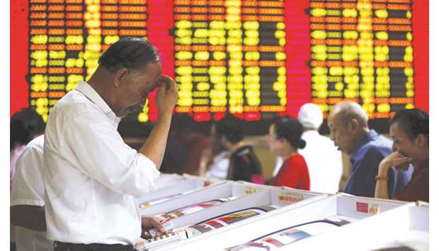 Investors look at computer screens showing stock information at a brokerage house in Shanghai. The Composite index closed down 1.3% to 2,938.14 points yesterday.