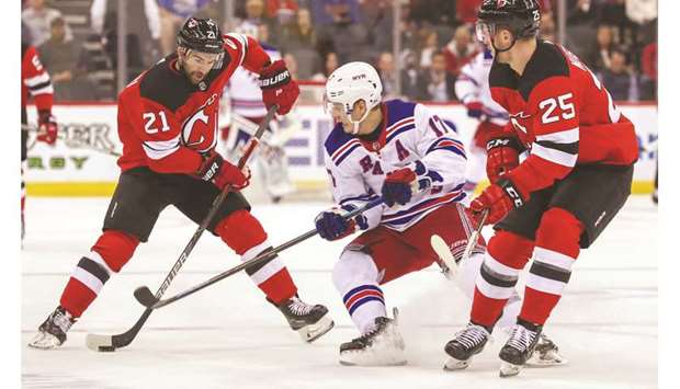 New Jersey Devilsu2019 Kyle Palmieri (left) skates with the puck while being defended by New York Rangersu2019 Jesper Fast (centre) during their game in Newark, United States, on Thursday. (USA TODAY Sports)