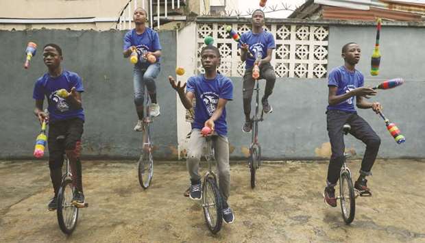 Members of the GKB academy, a unicycle club, juggle while balancing on their unicycles during a training session in Lagos.