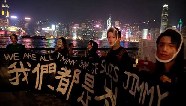 People wearing masks depicting Jimmy Sham hold a banner during an anti-government protest in Hong Kong yesterday
