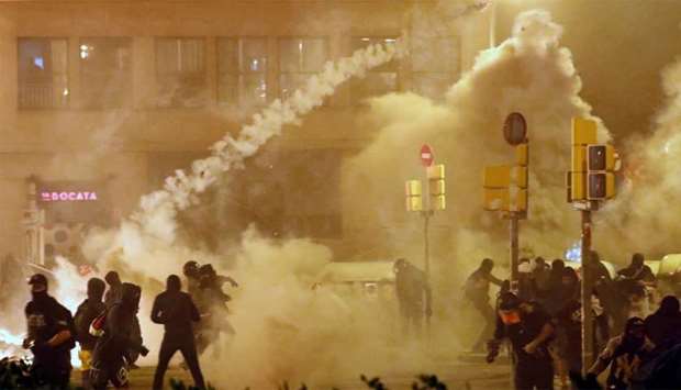 Catalan demonstrators throw back to the police a tear gas canister officer during Catalonia's general strike