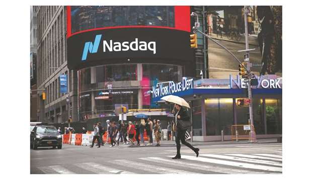 A pedestrian is crossing the street in front of the Nasdaq MarketSite in New York (file). Over the past 39 weeks, stocks and bonds markets have been hugging each other like no time since the early 1990s, data compiled by Ned Davis Research show.