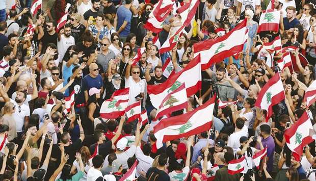 Demonstrators carry national flags and gesture during an anti-government protest in Beirut, yesterday.