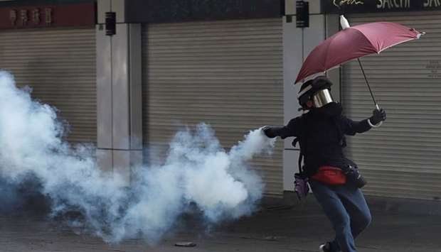 An anti-government demonstrator throws back a tear gas canister during a protest in Hong Kong