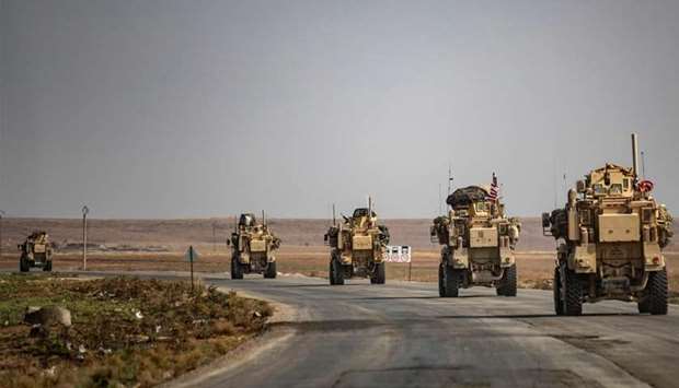 US military vehicles drive on a street in the town of Tal Tamr
