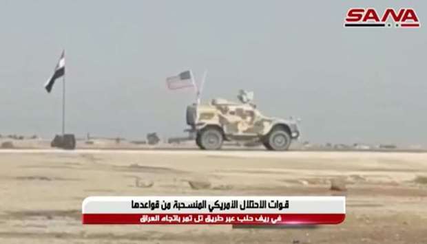A military vehicle bearing a US flag travels past a Syrian flag flying by a roadside in Tel Tamer, Syria in this still image taken from video. SANA via REUTERS
