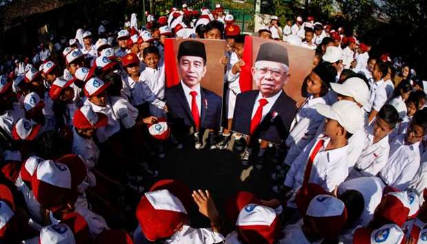 Students hold the pictures of Indonesian President Joko Widodo and Vice President Ma'ruf Amin during a ceremony following the yesterday's inauguration in Solo, Central Java province, Indonesia