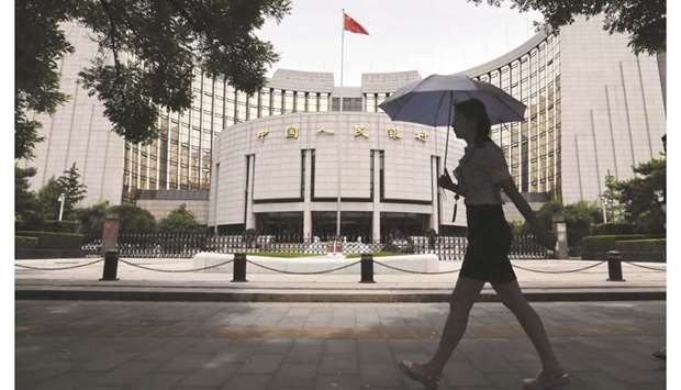 A pedestrian walks past the Peopleu2019s Bank of China headquarters in Beijing. The PBoC unexpectedly injected 200bn yuan ($28.29bn) through medium-term lending facility loans last week while keeping the lending rates unchanged.