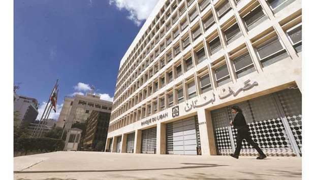 A woman walks outside of Lebanonu2019s central bank building in Beirut (file). The central bank will cut by half the governmentu2019s cost of servicing bonds the regulator holds in Lebanese pounds, the secretary general of the council of ministers, Mohammad Makiyeh, said in a televised news conference yesterday.