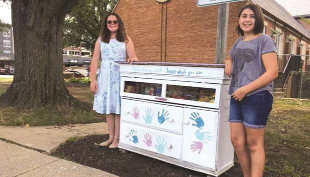 Amanda Santana, left, and Anna Rissi stand with their Little Free Pantry project in Alexandria, Virginia, in September 2019. Thomson Reuters Foundation/Carey L Biron