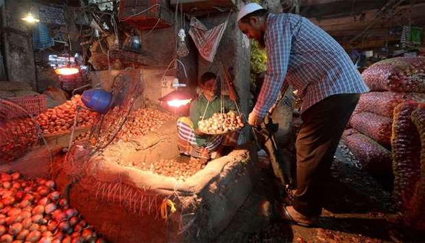 A salesman sells onions to a customer at Kawran Bazaar wholesale market in Dhaka