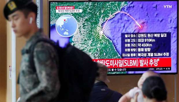 A South Korean soldier walks past a TV broadcasting a news report on North Korea firing a missile that is believed to be launched from a submarine, in Seoul