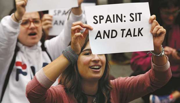 Supporters of Cataloniau2019s independence sit on a street holding placards during a protest outside Spanish government offices in Barcelona.