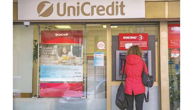 A customer uses an ATM at a UniCredit bank branch in Rome. UniCredit is looking at whether it can distance itself from its home countryu2019s stagnating economy and fractious politics by putting some of its most prized assets under one roof in Germany, people familiar with the matter say.