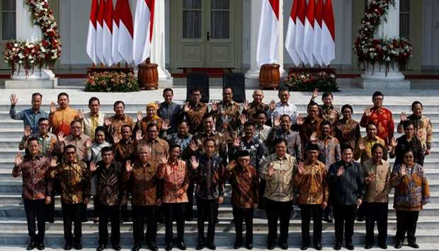 Indonesian President Joko Widodo, Vice President Ma'ruf Amin, and newly appointed cabinet ministers wave as they pose for photographers before the inauguration of new cabinet ministers for Widodo's second term, at the Presidential Palace in Jakarta