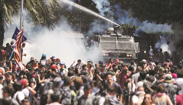 Demonstrators are sprayed by security forces with a water cannon during a protest against Chileu2019s state economic model in Santiago, Chile, yesterday.