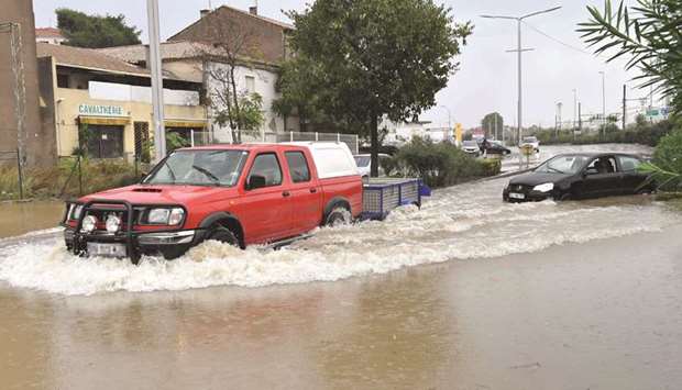 Vehicles drive through flood waters yesterday following overnight storms in Beziers, southern France.