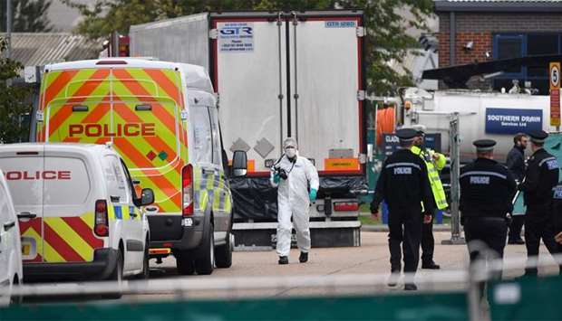British Police officers in forsensic suits work near a lorry, found to be containing 39 dead bodies, as they work inside a police cordon at Waterglade Industrial Park in Grays, east of London