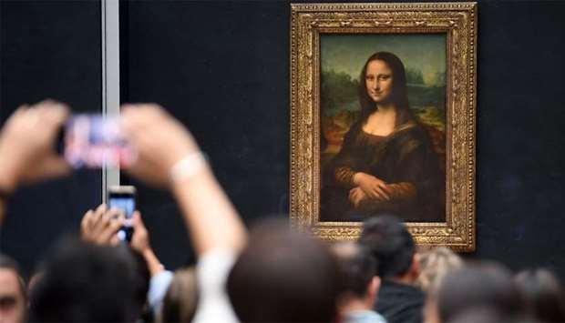 Visitors take photographs in front of The Mona Lisa (La Gioconda) after it was returned to its place at the Louvre Museum in Paris