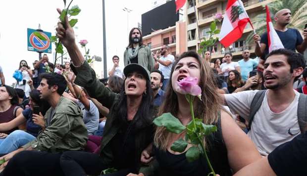 Lebanese actress and film director Nadine Labaki (C) holds a rose as she takes part with fellow demonstrators in an anti-government protest on a major bridge in the centre of the capital Beirut