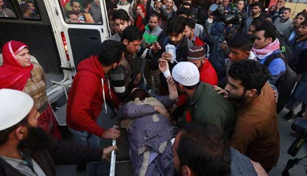 People rush a woman to a hospital for treatment after she was injured in a grenade blast in north Kashmir, in Srinagar