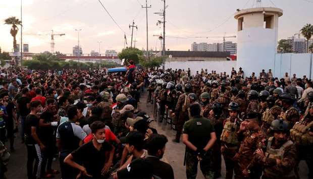 Demonstrators are seen in front of Iraqi security forces near Kerbala Governorate Building during a protest over corruption, lack of jobs, and poor services, in Kerbala