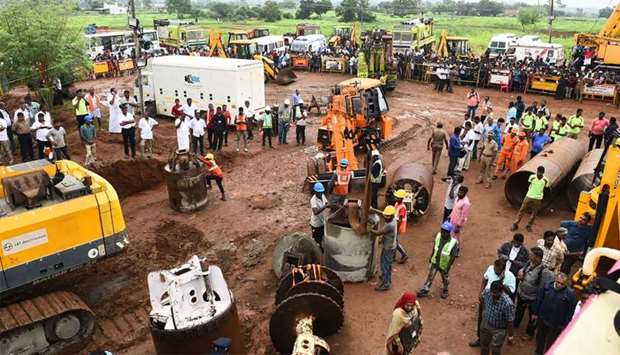 Rescue workers gather with heavy digging equipment during an operation to rescue a toddler stuck in a deep well near Manapparai town in Tiruchirappalli district, in India's southern Tamil Nadu state