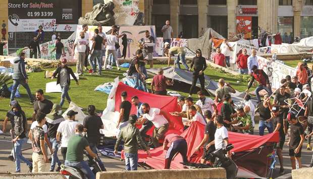 Men run as others destroy tents at a camp set up by anti-government demonstrators in central Beirut, yesterday.
