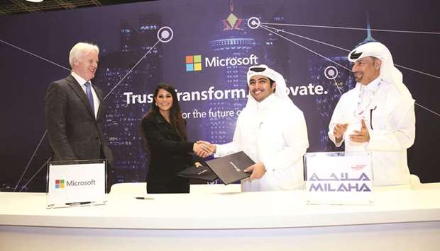 Milaha and Microsoft Qatar officials shaking hands after signing a partnership agreement.