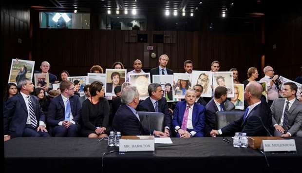 John Hamilton, vice president and chief engineer of Boeing Commercial Airplanes, and Boeing Chief Executive Dennis Muilenburg look back at family members holding photographs of Boeing 737 MAX crash victims as Hamilton and Muilenburg testify before a Senate Commerce, Science and Transportation Committee hearing on ,aviation safetyu201d and the grounded 737 MAX