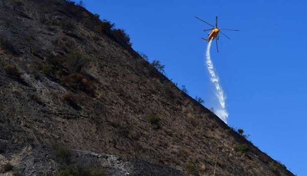 A helicopter makes a water drop over hillsides near in Los Angeles