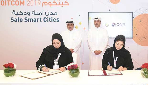 HE the Minister of Transport and Communications Jassim Seif Ahmed al-Sulaiti and QNB Group acting CEO Abdullah Mubarak al-Khalifa look on as MoTCu2019s Mashael al-Hammadi, and QNBu2019s Heba al-Tamimi sign the MoU yesterday at Qitcom 2019.