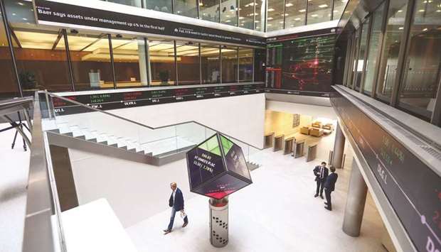 Visitors walk past an illuminated rotating cube displaying share price information in the atrium of the London Stock Exchange Group offices in Paternoster Square. The FTSE 100 closed 1.1% down at 7,248.38 points yesterday.