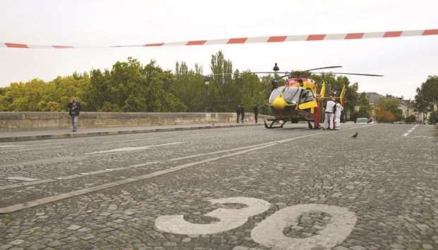 Emergency personnel are seen stand near an air ambulance helicopter on the Pont Marie, near the Paris police headquarters.