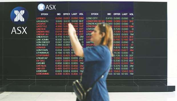 A woman takes a photograph as an electronic board displays stock information at the Australian Securities Exchange in Sydney (file). The S&P/ASX 200 index dived 2.2%, or 146.9 points, to 6,493 yesterday, its lowest close in over a month.