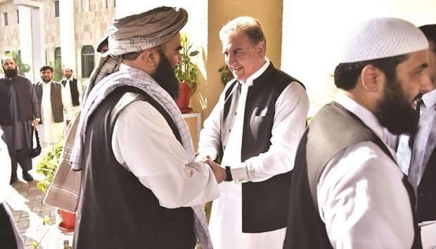 In this handout released by the foreign ministry shows Foreign Minister Shah Mehmood Qureshi receiving members of the Taliban delegation in Islamabad.