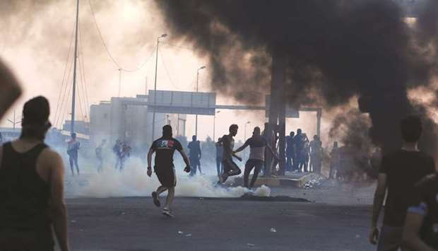 Demonstrators disperse as Iraqi security forces use tear gas during a protest after the lifting of the curfew, following four days of nationwide anti-government protests that turned violent, in Baghdad, yesterday.