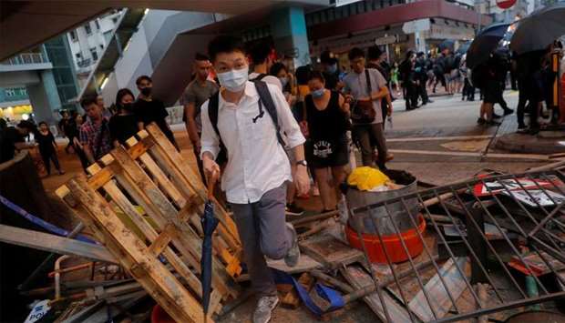 People walk over a barricade in Hong Kong, China