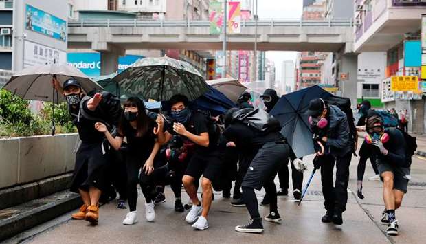 Anti-government protesters take cover while riot police use rubber bullets to disperse them during a demonstration following a governmentu2019s ban on face masks under emergency law, at Prince Edward, in Hong Kong.