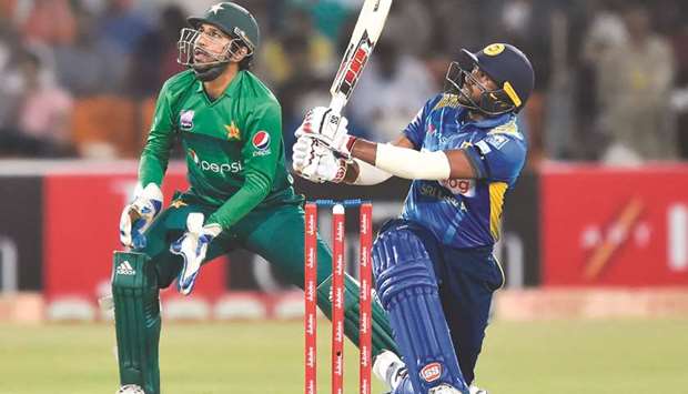 Sri Lankau2019s Bhanuka Rajapaksa plays a shot as Pakistanu2019s captain and wicketkeeper Sarfraz Ahmed looks on during the second Twenty20 match at the Gaddafi Cricket Stadium in Lahore yesterday. (AFP)