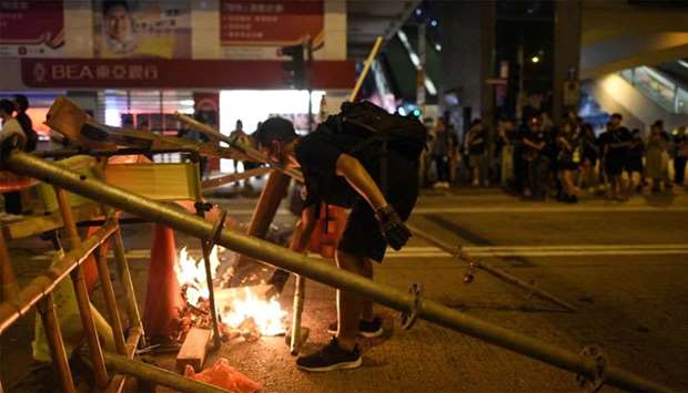 A protester setting fire to a barricade in the street during a stand off with police near the Mongkok police station in Hong Kong